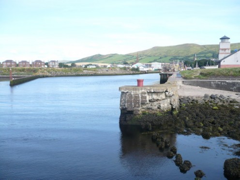 Looking into the harbour at Girvan. To the right is the Scottish Water building and, in the distance is the spire of the parish church with the Stumpy Tower further to the right of the picture.