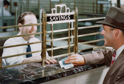 Vintage banking photo. Notice the bars near the teller? Banks today do not have bars for the banking companies feel that bars are too harsh