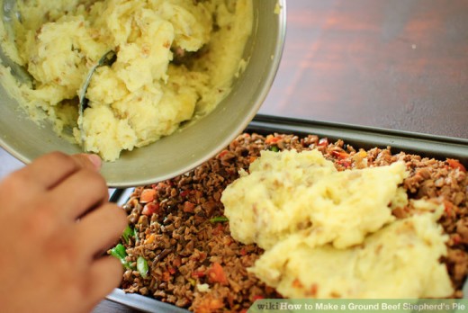Spooning Mashed Potatoes Over Prepared Meat and Vegetable Mixture