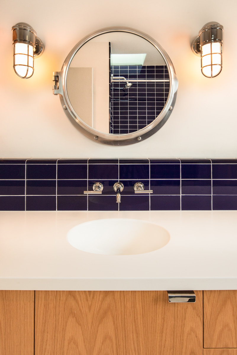 This porthole-shaped mirror gives the bathroom a nautical feel. Its circular shape accentuates the circles in its vicinity.