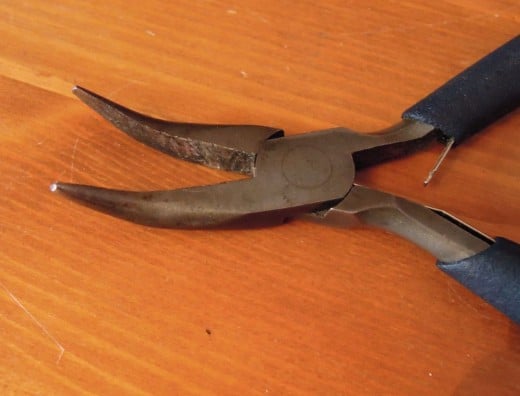 A pair of bent nosed pliers.
