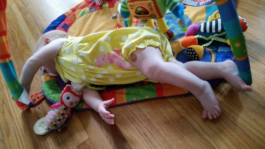 Reaching and rolling are fun and productive. Her mom places items just out of reach to encourage Imogen to roll.