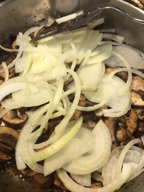 After a couple of minutes, add the onions and stir well. You're going to cook the mushrooms and onions together, scraping the bottom of the pan, for about ten minutes.