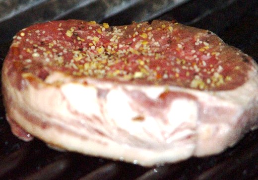 A thick steak topped with tasty seasoning, ready for grilling.