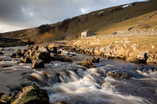 A characteristic Dales stone barn keeps watch over the river - some have seen conversion to homes, although stringent planning laws in the Dales National Park ensure nothing untoward is done, and keeps to the character of the area 