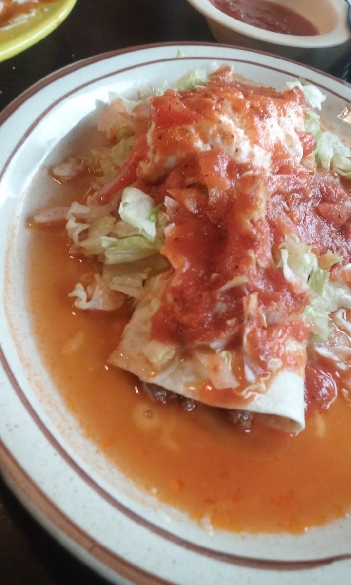 beef burrito with shredded lettuce, sour cream and lots of tomato sauce