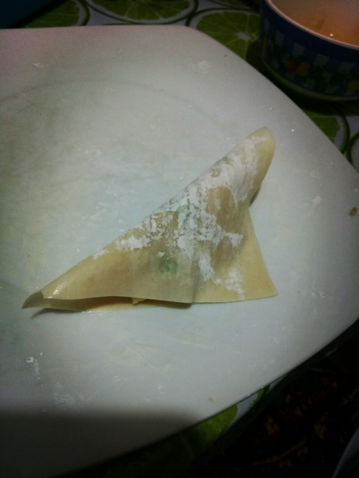 3. Brush the sides of the wrapper with water then fold it over until both ends meet. Lightly press it to close. 