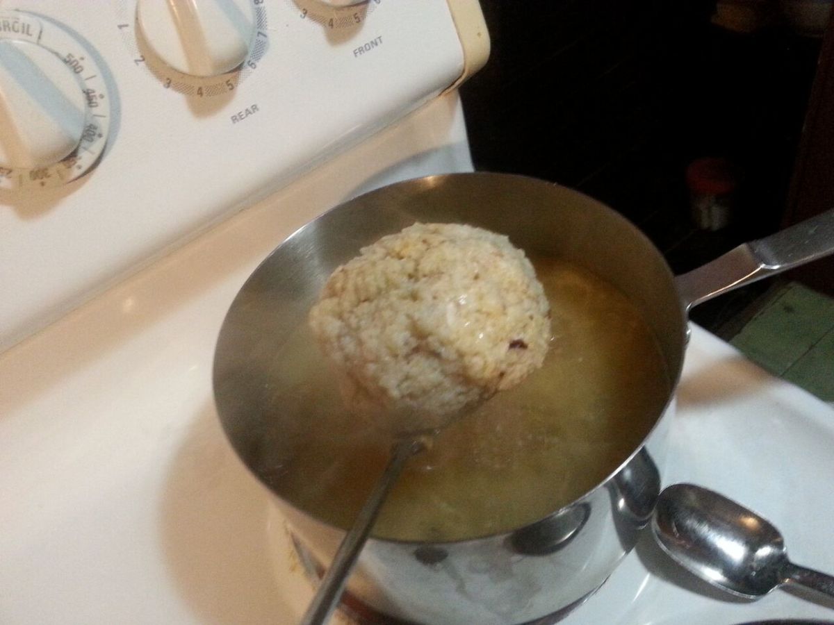 Using a slotted spoon to transfer matzo balls to the pot of chicken broth