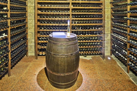 Vintage-style cellar with stone tiles and re-purposed wine barrel for a table.