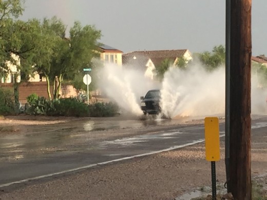 Car driving through flooding following an Arizona summer monsoon storm.  These storms result in insurance claims for damage to homes and vehicles.