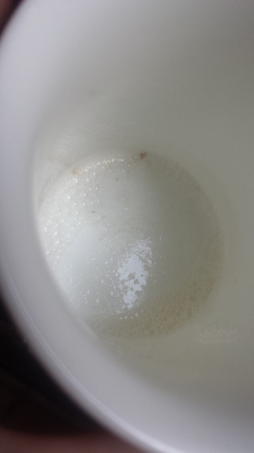 Mug left to dry upright, with some suds in the bottom. A greasy deposit can be seen on the bottom after the suds have dried.