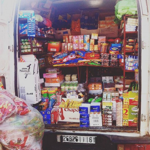 A van delivering supplies to a shop.  Dry goods such as tea, cookies and chocolate are sold in the store.  Other merchandise includes cleaning supplies and basic toiletries.