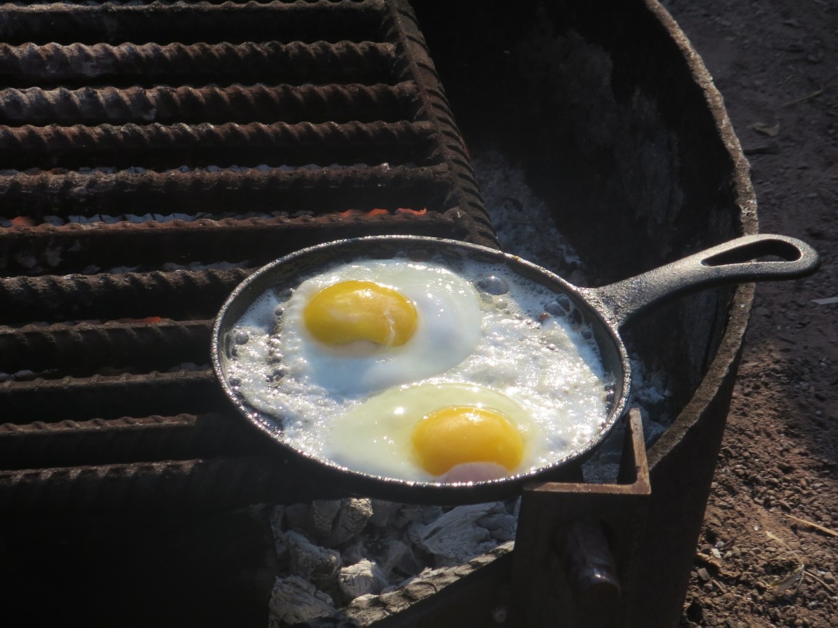 The aromas of coffee, ham or bacon, and eggs cooking over an open fire awakens campers for breakfast.. 