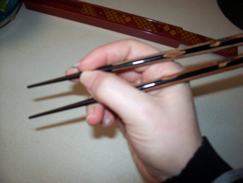 Don't hold the chopsticks so close to the front.  See how it doesn't give you much range of motion?