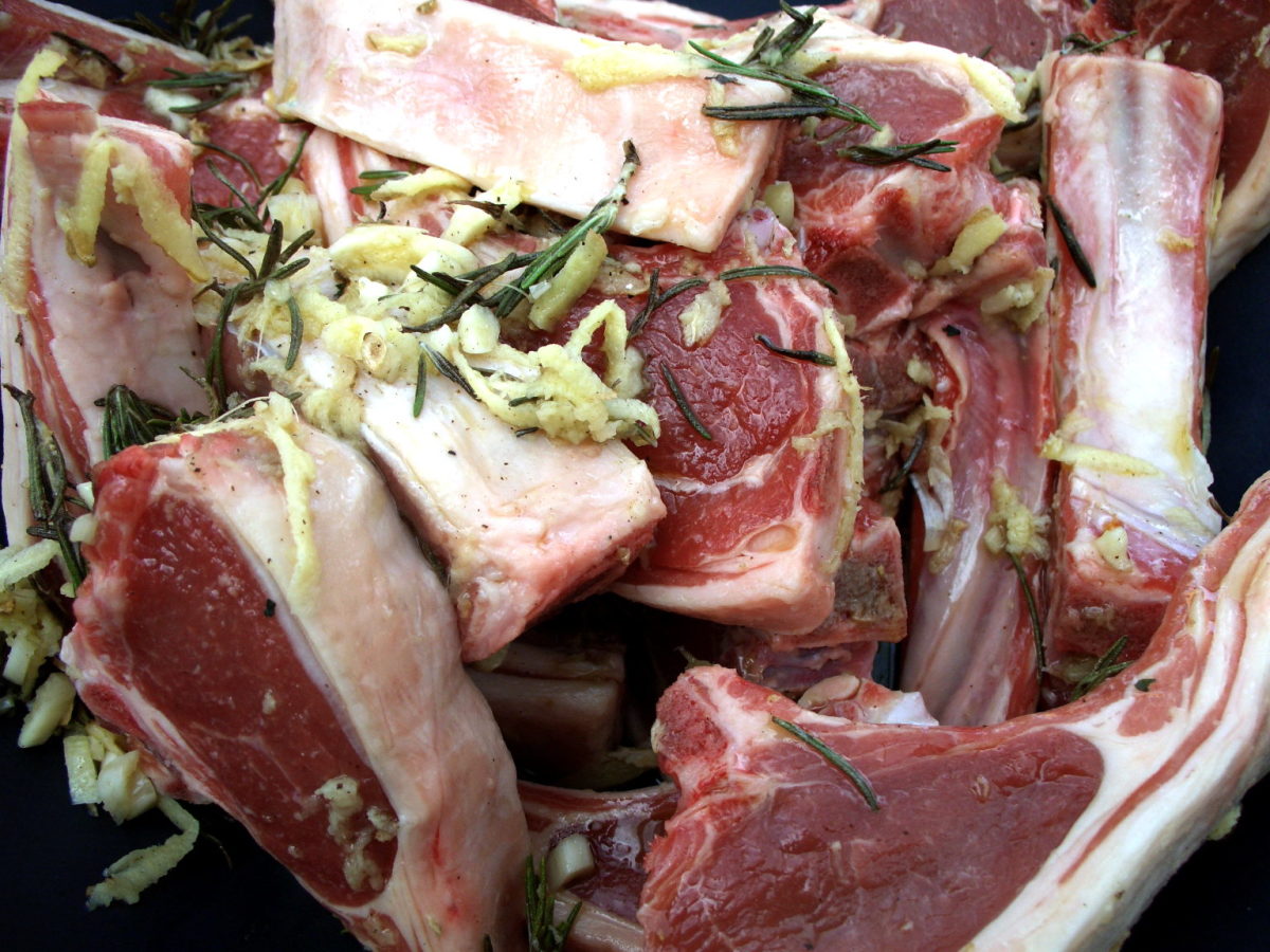 Raw lamb cutlets with shredded ginger and rosemary.