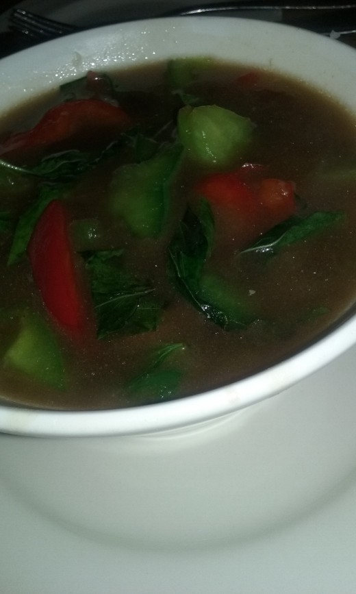 On the side, a bowl of brown sauce that includes red bell peppers, green bell peppers and scallions. 
