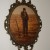 A vintage bubble glass frame, pictures a man looking down at his crops soil.