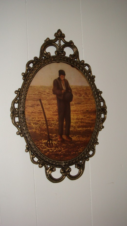 A vintage bubble glass frame, pictures a man looking down at his crops soil.