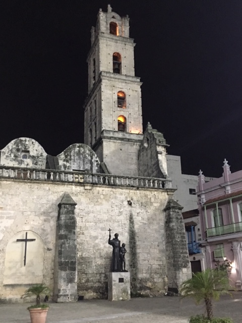 Night photo of Statue of Fray Junípero Serra with Juaneño Indian Boy in the Plaza de San Fransisco de Asís. A statue of Francis de Asis once stood on top of the bell tower.