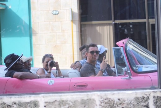 Riding in a pink convertable through Old Havana, images reflected in the windows of one of the more modern buildings circa '50s.