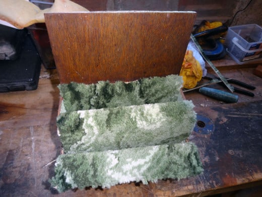 Having folded the carpet into a concertina shape to fit the pockets, pushing it into place prior to securing with upholstery nails.