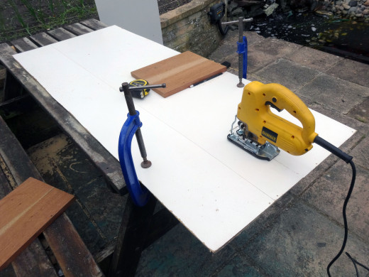 Using a jig saw to cut the white faced hardboard to size.