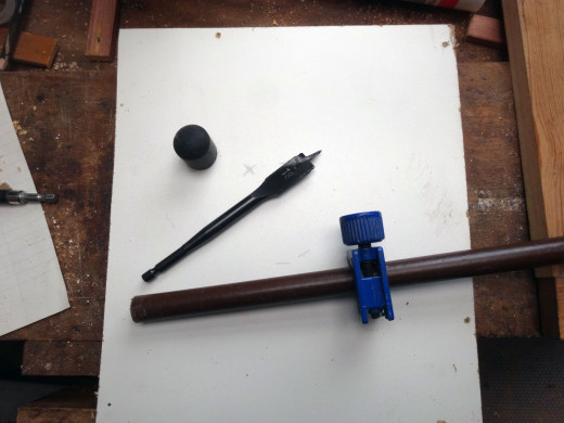 Metal rod to be cut with a pipe cutter, rubber foot for fitting to the bottom of the rod, and flat wood head bit to cut the hole for the rod.