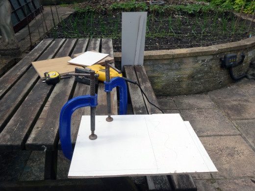 Clamping up to cut the white faced hardboard to size with a jig saw.
