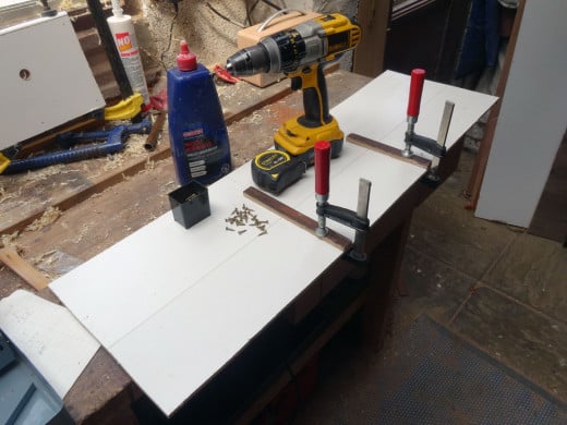 Fitting shelf supports to one of the white faced hardboard side panels.