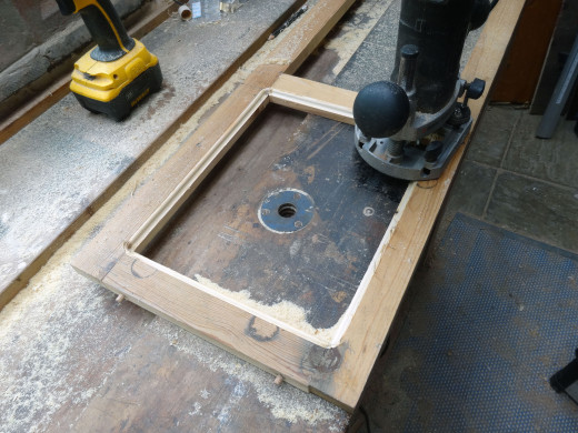 The decorative mouldings being routed on the reverse side to the glass recess; this router bit is self-guiding, so no clamp guide needed.