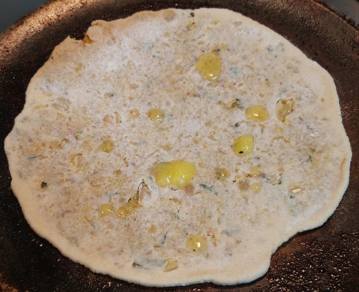 Put rolled paratha on a hot tawa or pan. Add some drops of oil or ghee and fry.