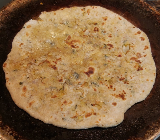 Fry and cook both sides once or twice. Press paratha using spatula for uniform cooking. You can see some brown spots on paratha. Repeat the same process for all parathas. 
