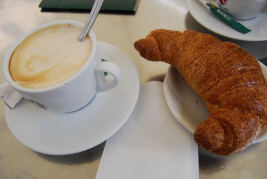 A cup of cappuccino and a croissant is a perfect breakfast in the morning. 