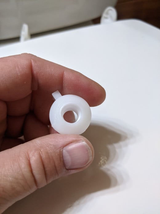 Nut onto screw, rounded end facing toilet. Round end fits into toilet around screw.