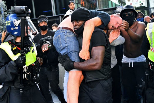 Courtesy of REUTERS/Dylan Martinez. Patrick Hutchinson, carrying a wounded far rightist to safety.