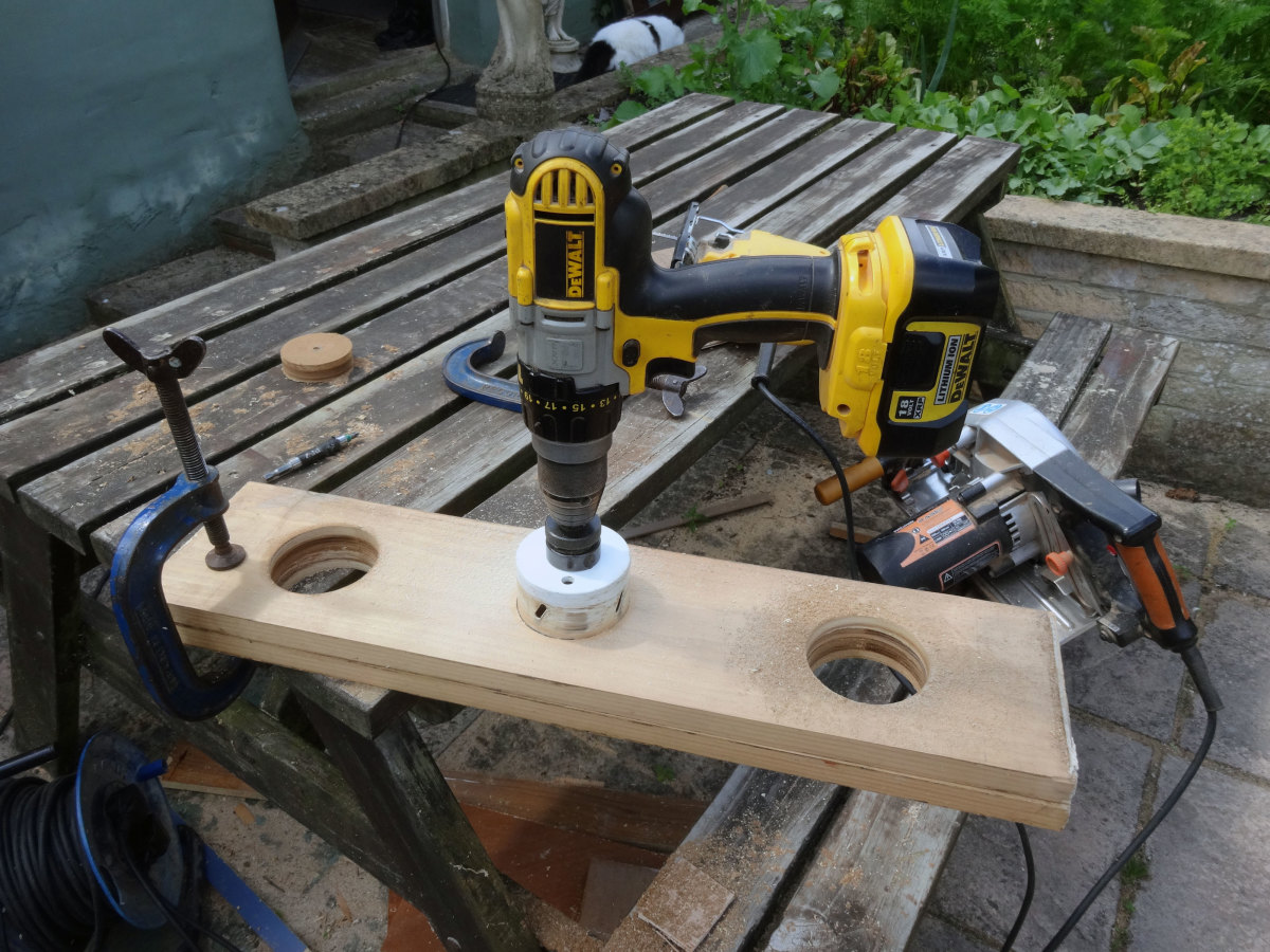 Cutting access points, with a large hole saw, in the two large pieces of recycled wood being used to make teh cable management trough