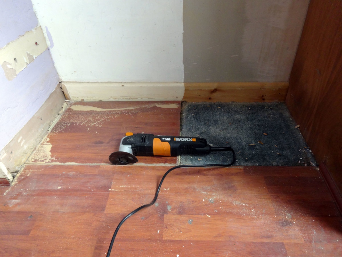 Using my sonic saw to square off the existing, so as to add a new strip of laminate flooring in the alcove