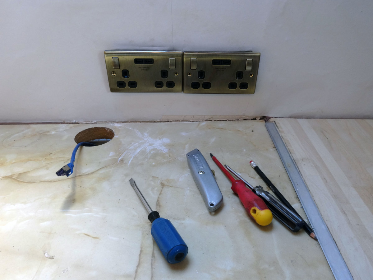 Turning off the power, unscrewing the wall sockets, and nipping up to 1/2 inch wallpaper behind the socket, for a neat finish