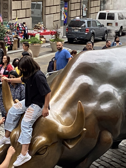 My photo of young girl sitting on the bull near Wall Street during our family tour.