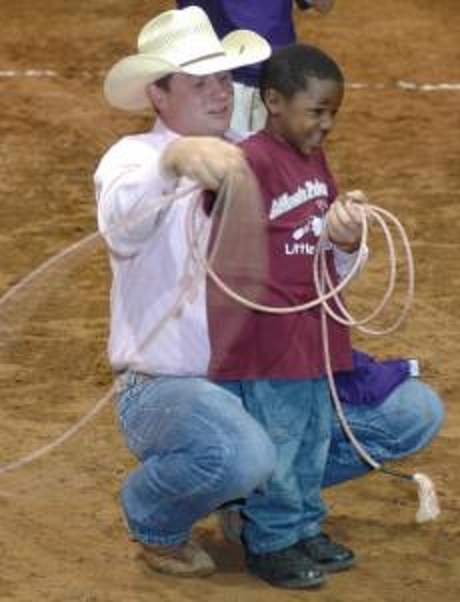 Photo by Jim Williamson. Shaun Smith helped a young cowboy learn how to rope at the Four States Fairgrounds.