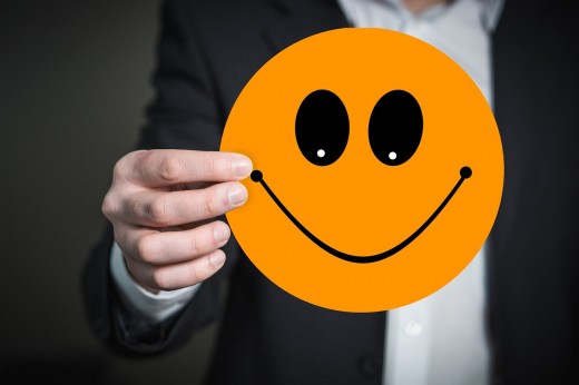 A person holding an oversized smiling face emoji sticker in front of the camera - my representation of the new faces in Romanian politics, who are more active on social media, and super interested in social activism - Image by Gerd Altmann from Pixab