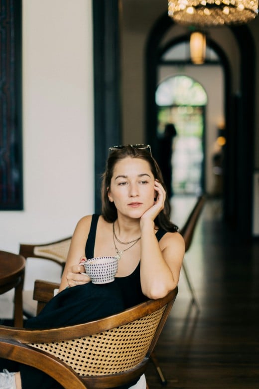 Woman in black tank top sitting on brown wooden chair