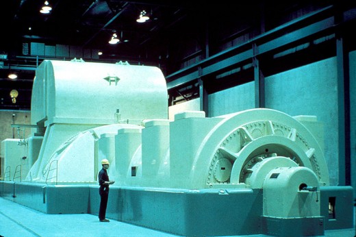 Steam Turbine Generator. The Steam enters from the large structure in the middle, turns a turbine (fan) which then turns the generator. The generator is the structure the man with the clipboard is standing in front of.