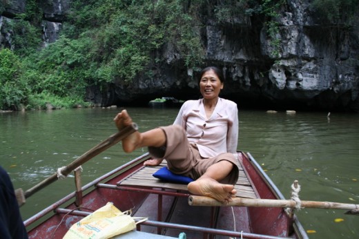 My helms woman rowing with her feet on the Tam Coc Cave Trip