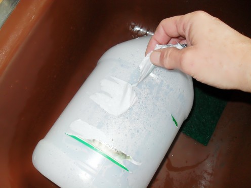 Peel away the label as the water loosens the paper from the recycled bottle.