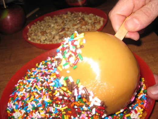 Try to coat the toppings onto the caramel apple. 