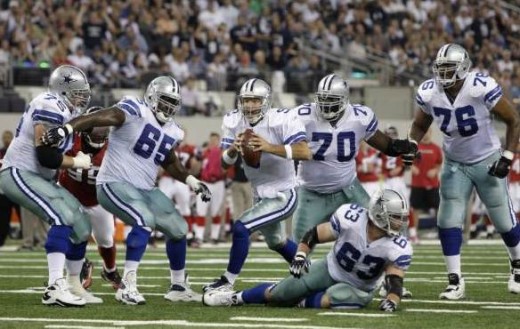 Dallas Cowboys quarterback Tony Romo (9) looks for an open receiver as he scrambles protected by his offensive line in the first half of an NFL football game against the Atlanta Falcons, Sunday, Oct. 25, 2009, in Arlington, Texas. (AP Photo/LM Otero)