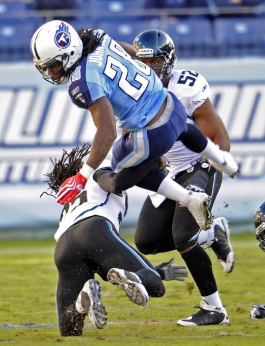 Tennessee Titans running back Chris Johnson (28) is tripped up by Jacksonville Jaguars safety Reggie Nelson, lower left, in the first quarter of an NFL football game in Nashville, Tenn., Sunday, Nov. 1, 2009. (AP Photo/John Russell)