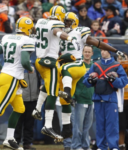 Green Bay Packers running back Ryan Grant (25) celebrates his touchdown with teammate Brandon Jackson (32) as Packers quarterback Aaron Rodgers (12) passes them during the first half of an NFL football game against the Chicago Bears in Chicago, Sunda