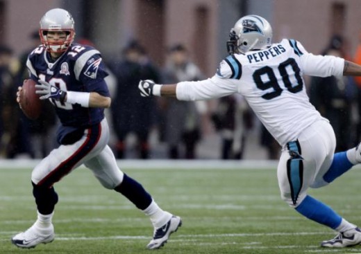 New England Patriots quarterback Tom Brady (12) scrambles as he tries to elude Carolina Panthers defensive end Julius Peppers (90) during the first half of an NFL football game in Foxborough, Mass., Sunday, Dec. 13, 2009. (AP Photo/Charles Krupa)